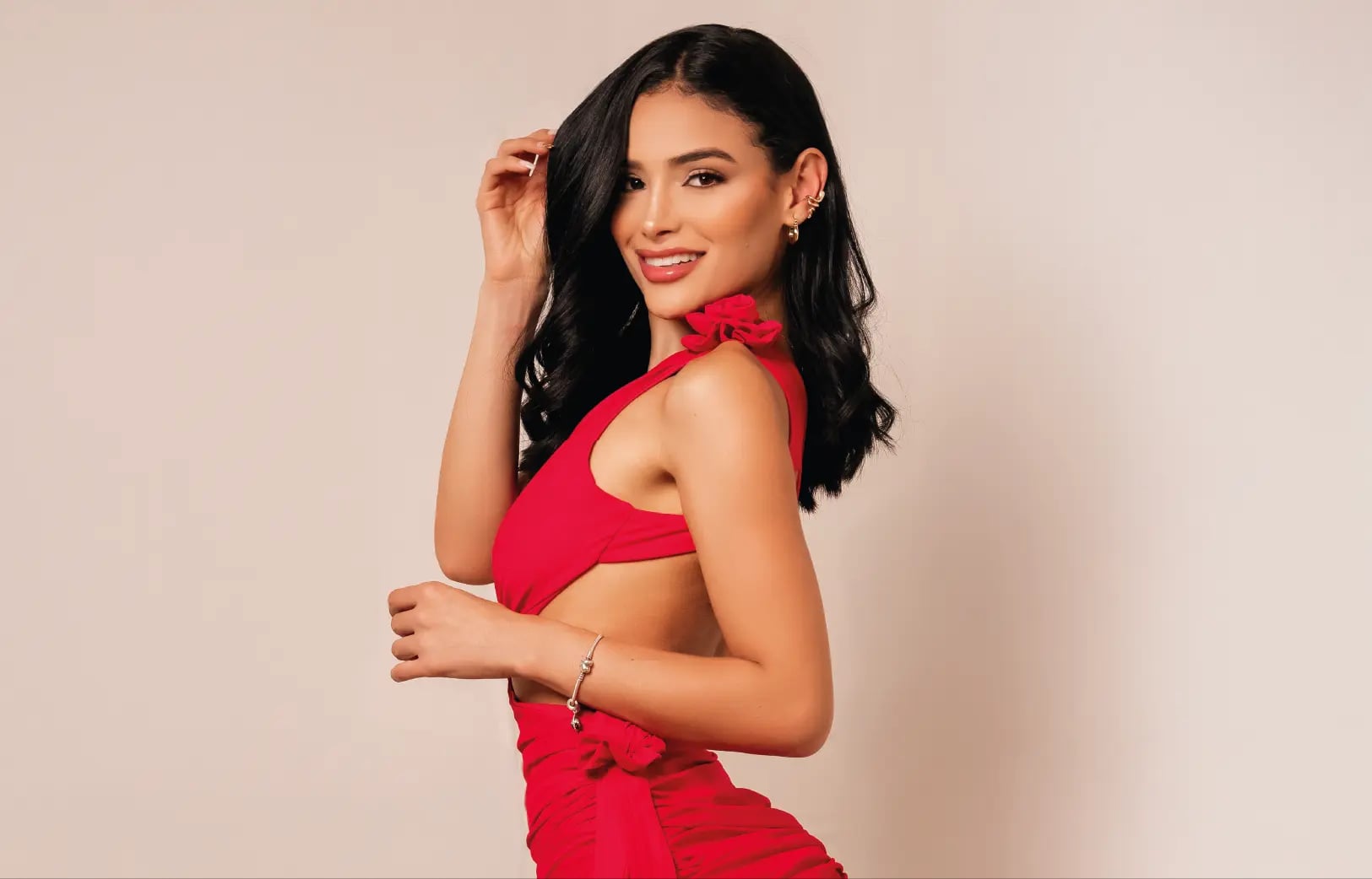 Modelo de Models 1A sonriendo en estudio con vestido rojo sobre fondo neutro