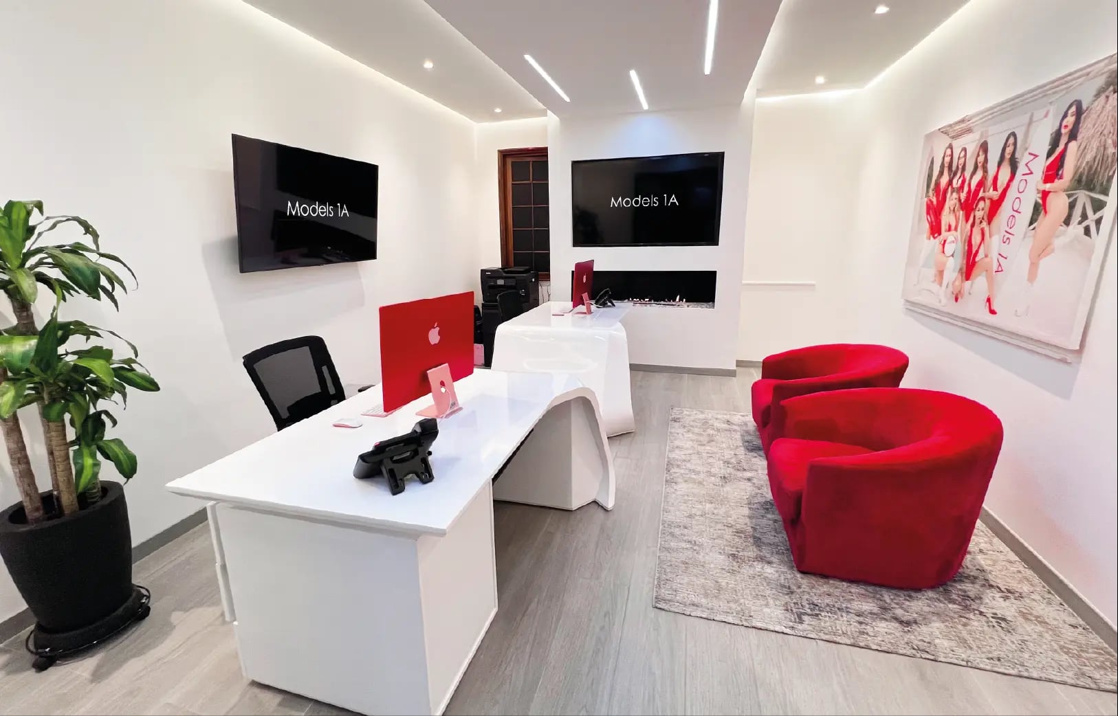 Recepción y oficinas de Models 1A con escritorios blancos y sillas rojas