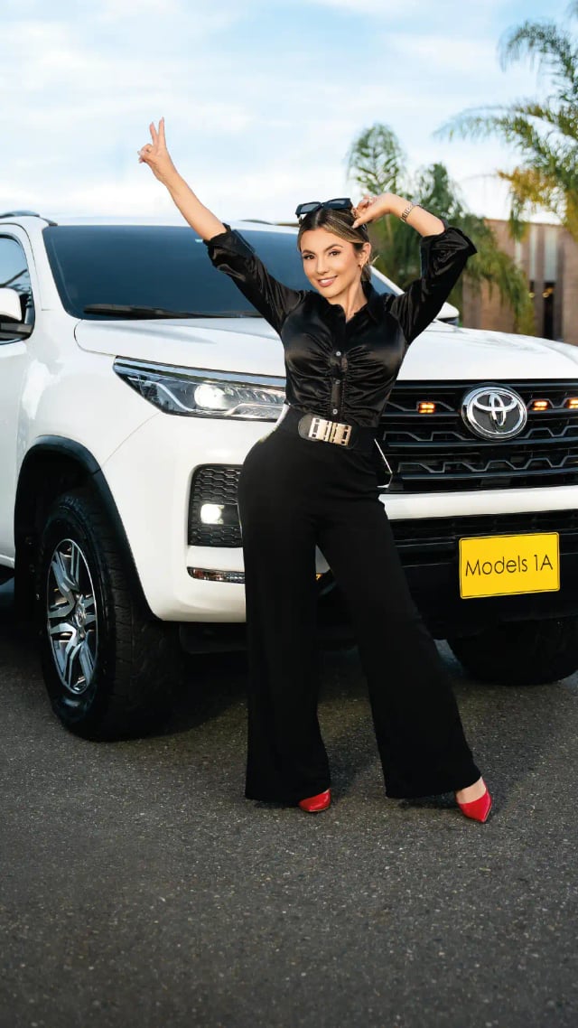 Modelo profesional de Models 1A posando frente a camioneta Toyota blanca